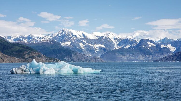An iceberg in the Columbia Bay, with the mountains of the Chugach National Forest.. Climate Pivot Photo: Rich Miller